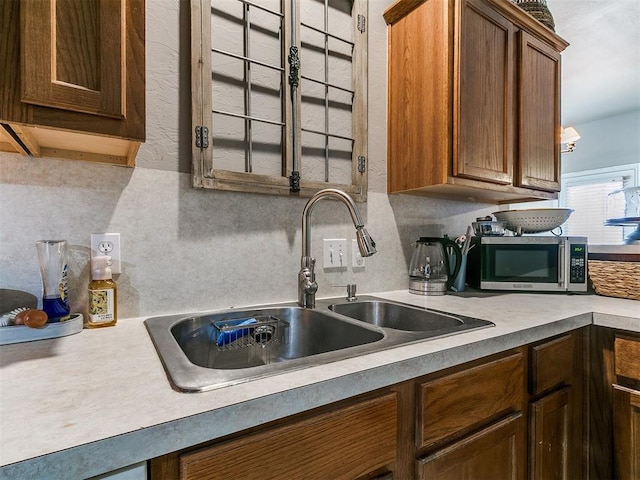 kitchen with stainless steel microwave, light countertops, and a sink