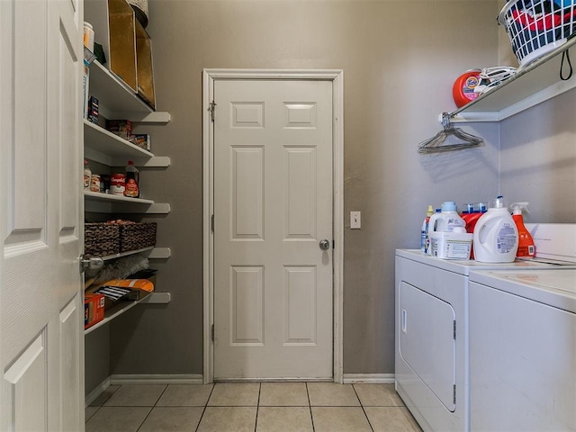 washroom featuring light tile patterned floors, baseboards, cabinet space, and separate washer and dryer