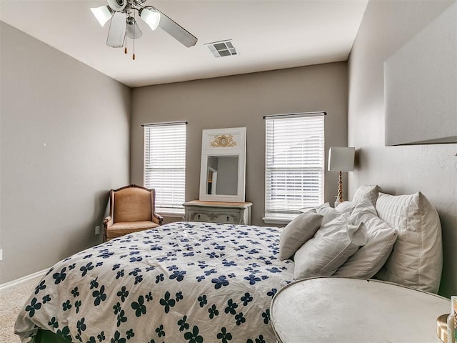 carpeted bedroom with multiple windows, a ceiling fan, visible vents, and baseboards