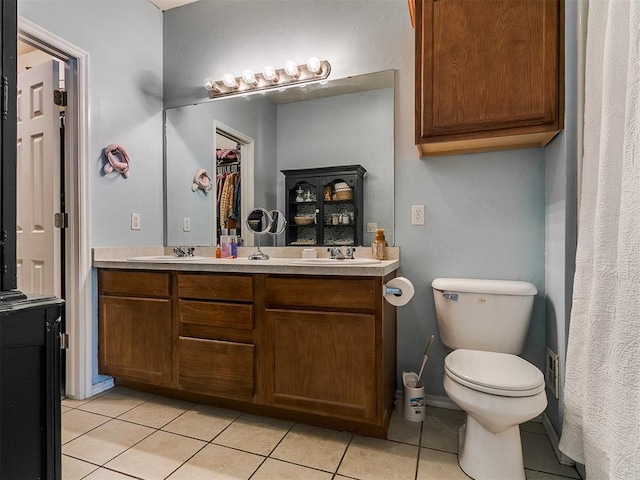 bathroom with tile patterned flooring, double vanity, toilet, and a sink