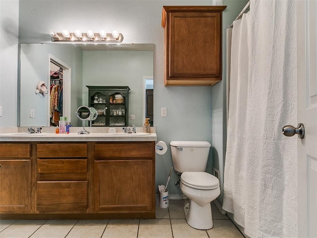 bathroom featuring tile patterned floors, double vanity, toilet, and a sink