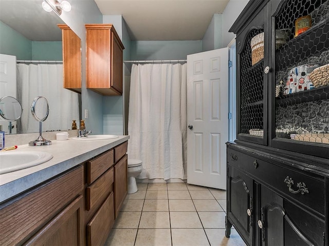 full bath featuring tile patterned flooring, double vanity, toilet, and a sink