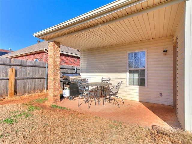 view of patio featuring a grill, outdoor dining space, and fence