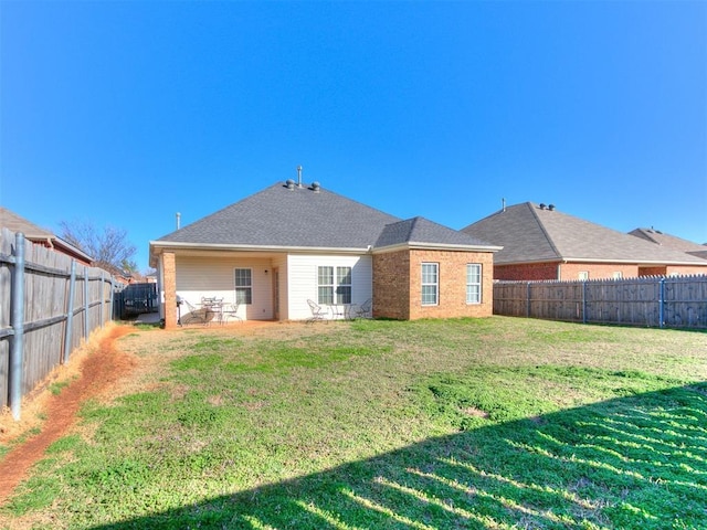 back of property with a yard, a fenced backyard, and brick siding