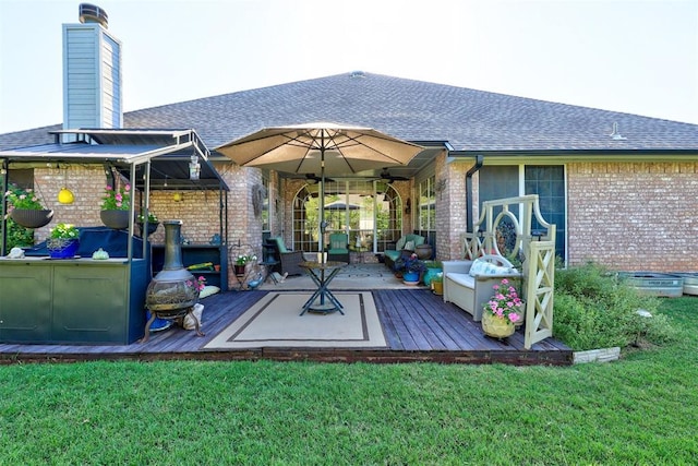 back of property featuring brick siding, a wooden deck, and a yard