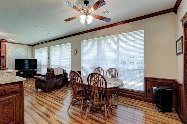 dining area with visible vents, wainscoting, light wood-style floors, and ornamental molding