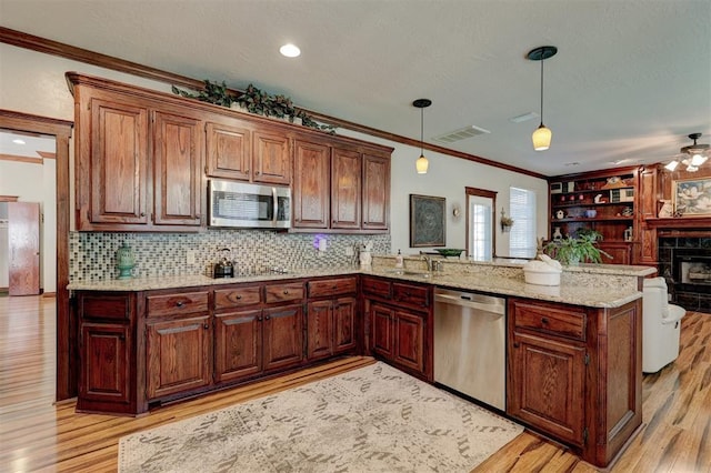 kitchen with visible vents, open floor plan, stainless steel appliances, a peninsula, and crown molding