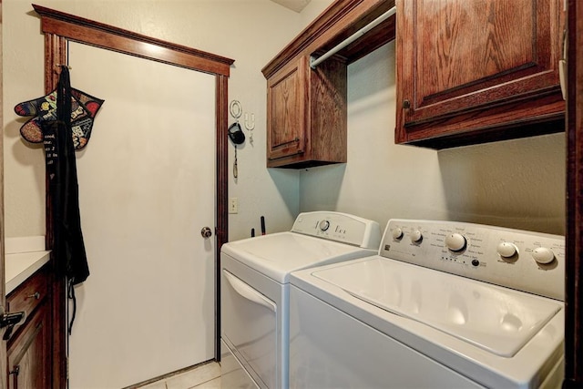 clothes washing area with light tile patterned floors, cabinet space, and washing machine and clothes dryer