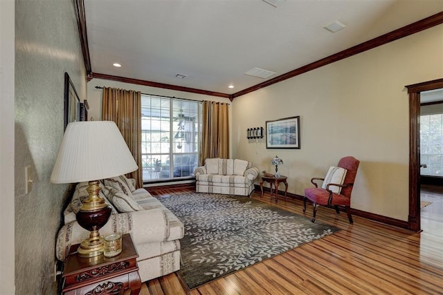 living room featuring visible vents, ornamental molding, baseboards, and wood finished floors