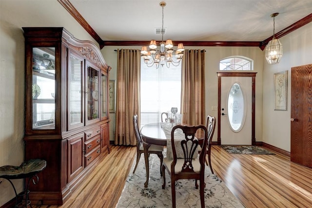 dining space featuring visible vents, light wood-style floors, an inviting chandelier, and ornamental molding