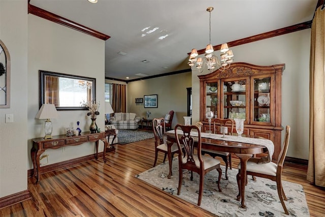 dining space with baseboards, an inviting chandelier, wood finished floors, and crown molding