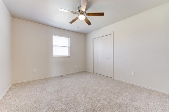 unfurnished bedroom featuring baseboards, a ceiling fan, a closet, and light carpet