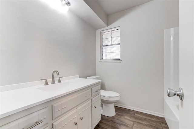 full bathroom with baseboards, a washtub, toilet, wood finished floors, and vanity