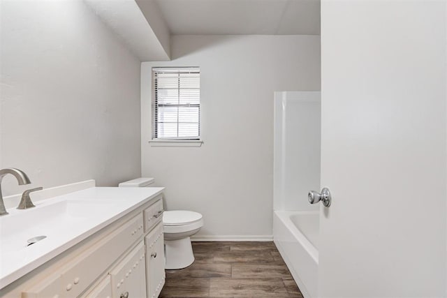 bathroom with vanity, toilet, wood finished floors, and baseboards