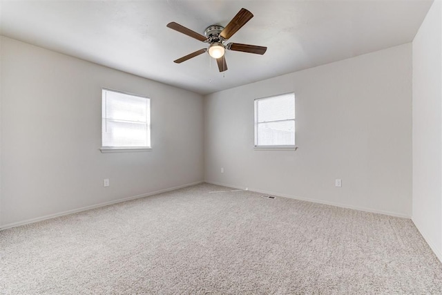 spare room with plenty of natural light, a ceiling fan, baseboards, and light carpet