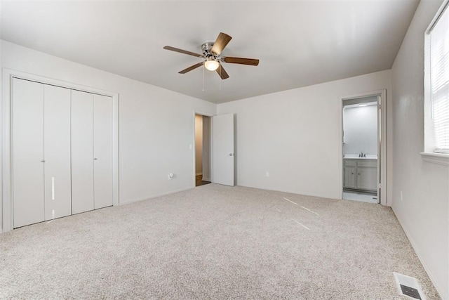 unfurnished bedroom with visible vents, a sink, a closet, connected bathroom, and carpet