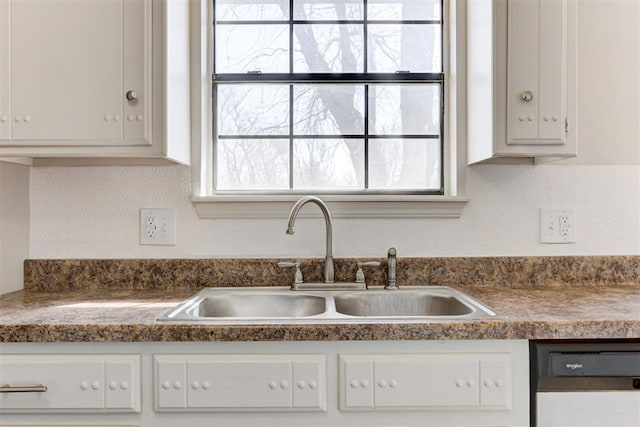 kitchen featuring a sink, dishwashing machine, dark countertops, and white cabinetry