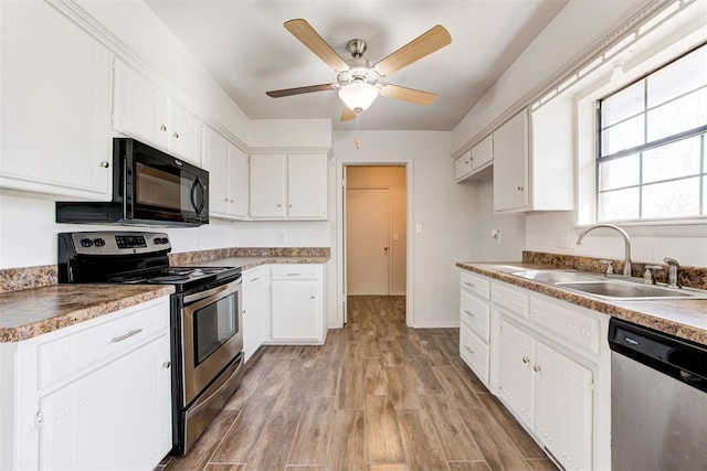 kitchen with a sink, stainless steel appliances, white cabinets, and light wood-style flooring