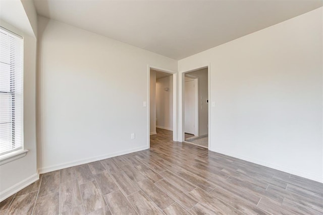 empty room featuring light wood-type flooring and baseboards