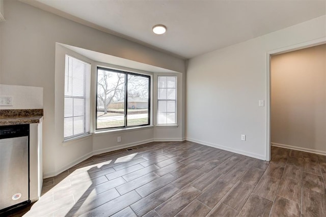 unfurnished dining area with dark wood-type flooring and baseboards