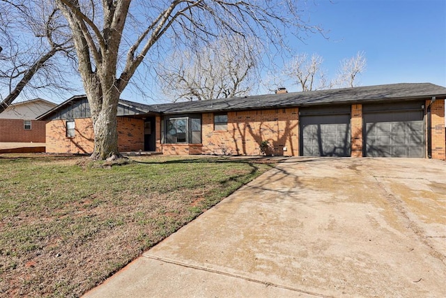 mid-century home featuring a front yard, driveway, a chimney, a garage, and brick siding