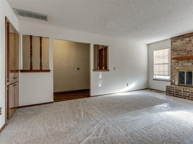 unfurnished living room featuring visible vents, a fireplace, a textured ceiling, and carpet