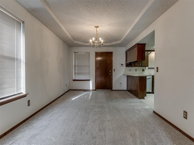 interior space with baseboards, a tray ceiling, light carpet, an inviting chandelier, and a textured ceiling