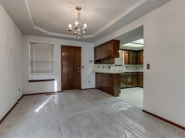 kitchen with a tray ceiling, a textured ceiling, a chandelier, and light countertops