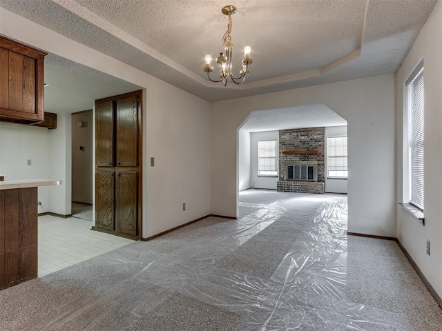 unfurnished dining area with light colored carpet, a textured ceiling, and a tray ceiling