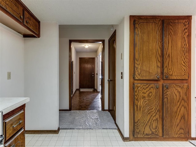 hall with baseboards and a textured ceiling