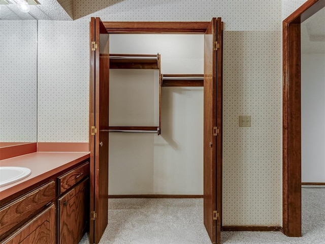 bathroom featuring baseboards, vanity, and wallpapered walls