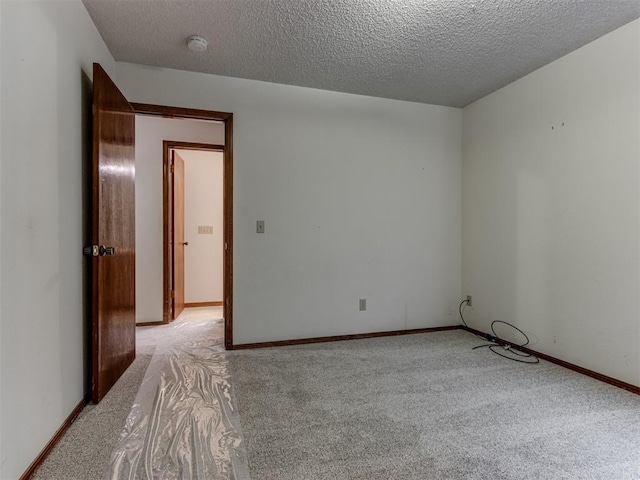 empty room with baseboards, light colored carpet, and a textured ceiling