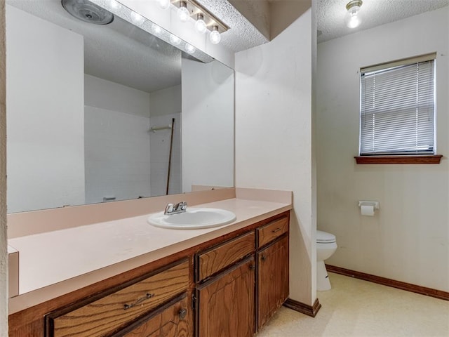 bathroom featuring baseboards, toilet, vanity, a textured ceiling, and a shower