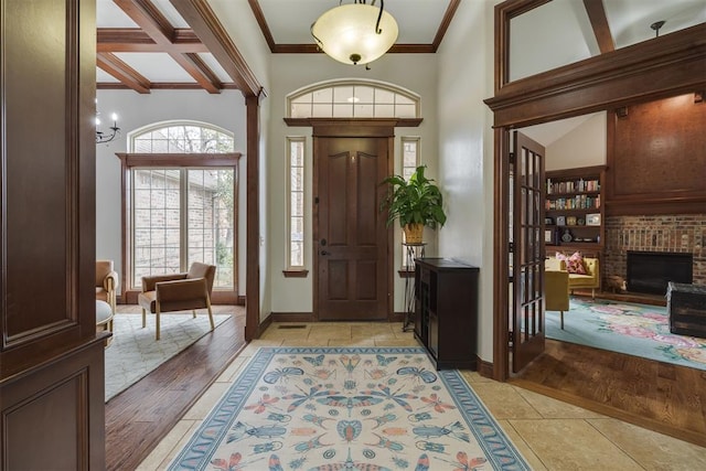 entrance foyer featuring beamed ceiling, baseboards, crown molding, and light wood finished floors