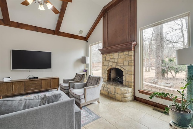 living room with visible vents, beamed ceiling, a stone fireplace, light tile patterned flooring, and a ceiling fan