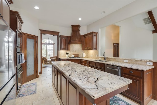 kitchen with visible vents, stainless steel appliances, a sink, custom range hood, and a center island