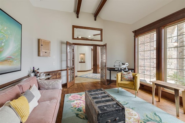 living area with french doors, lofted ceiling with beams, and wood finished floors