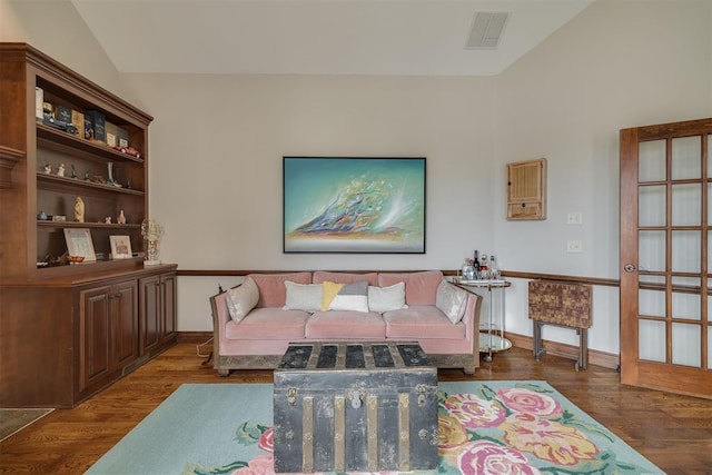 living area with vaulted ceiling, visible vents, baseboards, and wood finished floors