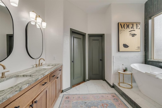 bathroom with a sink, a soaking tub, marble finish floor, and double vanity