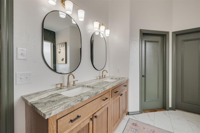 full bathroom with double vanity, marble finish floor, and a sink