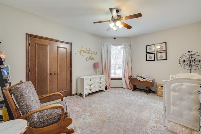 living area with baseboards, light carpet, and a ceiling fan