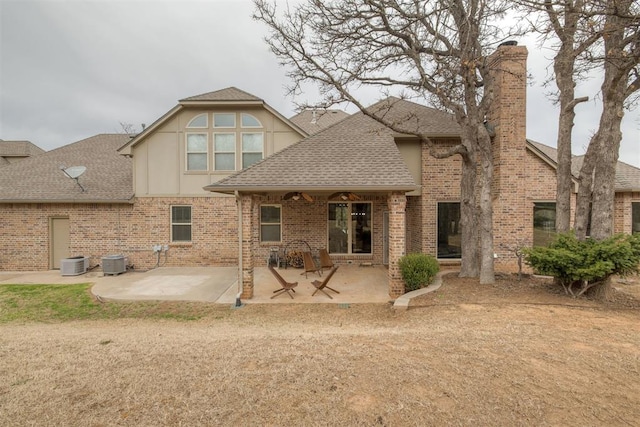 rear view of property featuring a patio, central air condition unit, brick siding, and a shingled roof