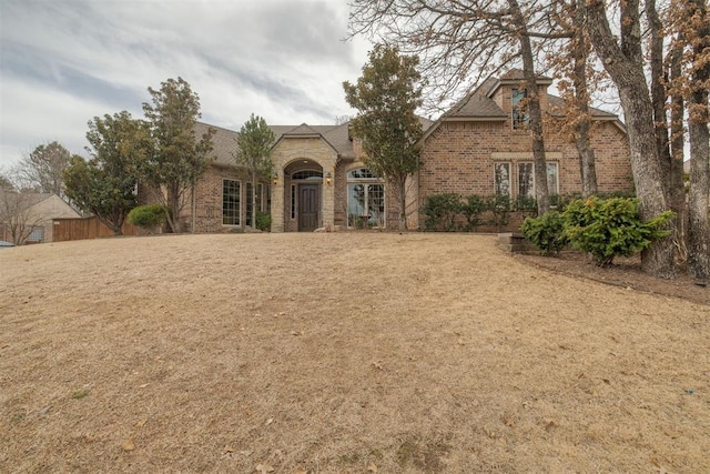 view of front of house with a front lawn, brick siding, and stone siding