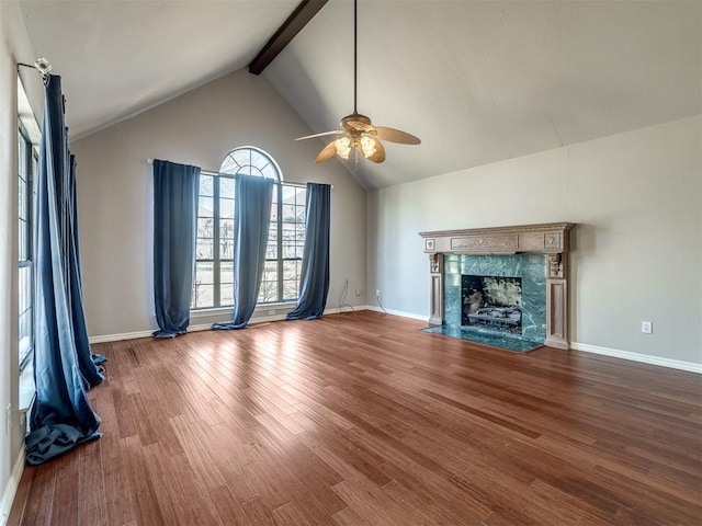 unfurnished living room featuring beam ceiling, high vaulted ceiling, a ceiling fan, wood finished floors, and a high end fireplace