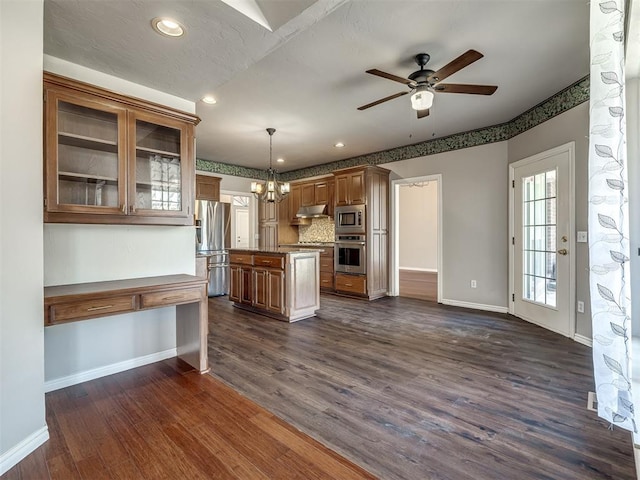 kitchen featuring dark wood-style floors, baseboards, under cabinet range hood, appliances with stainless steel finishes, and ceiling fan with notable chandelier