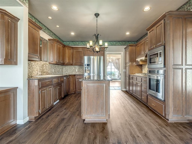 kitchen with dark wood-style flooring, a sink, appliances with stainless steel finishes, a notable chandelier, and a center island