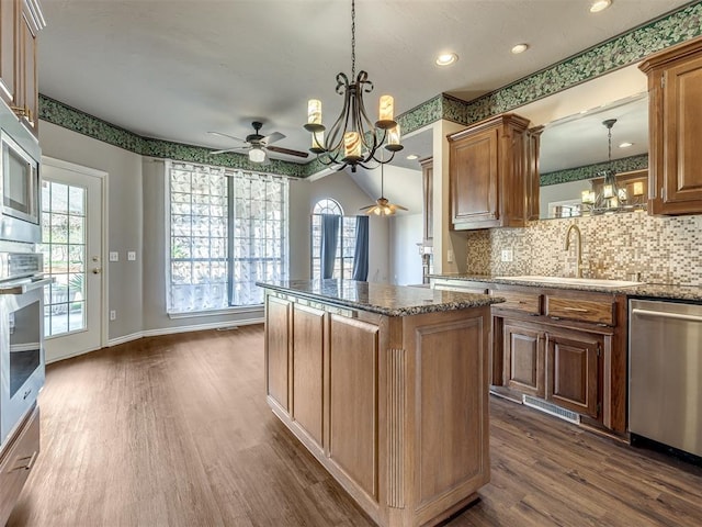 kitchen featuring dark wood-style flooring, a sink, dishwasher, ceiling fan with notable chandelier, and a center island