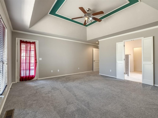 carpeted spare room featuring visible vents, a tray ceiling, a ceiling fan, and ornamental molding