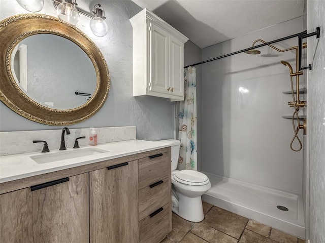 bathroom with toilet, stone tile floors, a stall shower, and vanity