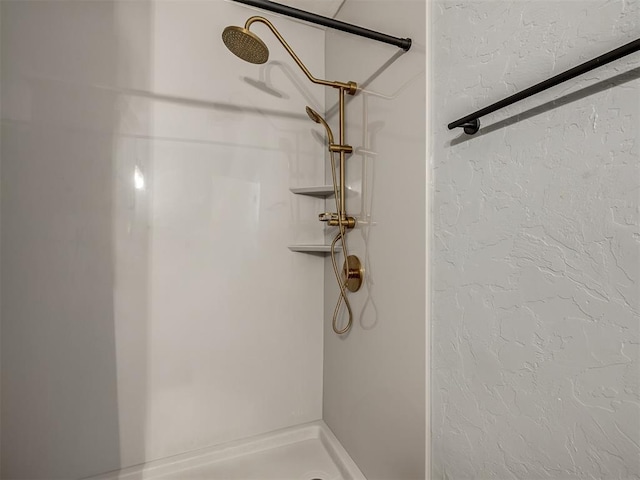 bathroom with a stall shower and a textured wall